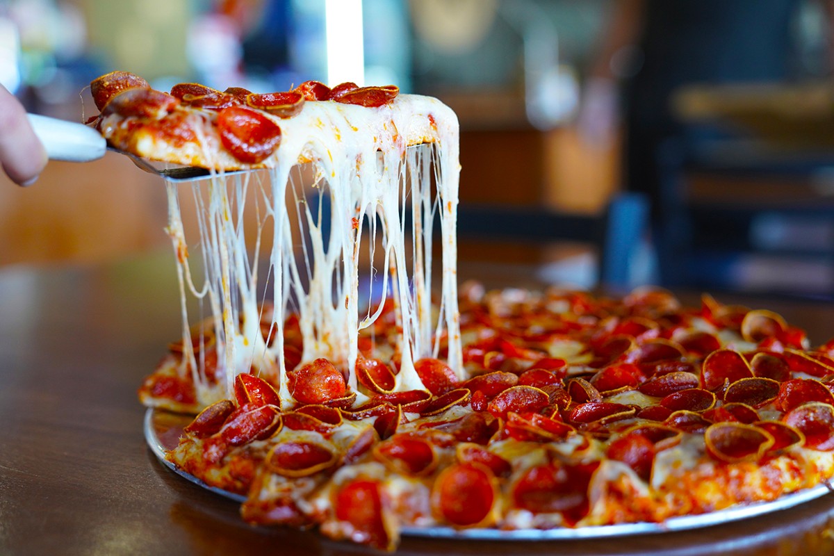 A Mountain Mike's slice oozing cheese as its pulled from a pie.