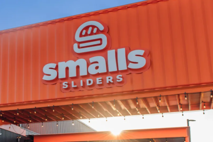 The exterior of a smalls sliders restaurant built with an orange shipping container and a burger logo on the front